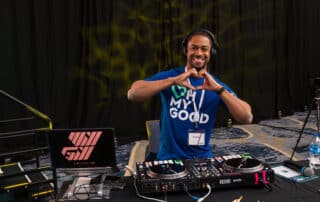 Corporate DJ WIll Gill doing a heart gesture in front of his turntables