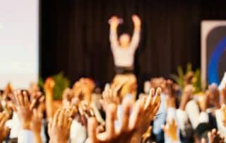 People raising their hands during sales kickoff event