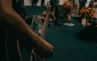 A person holding a guitar is a member of a live bands for corporate events