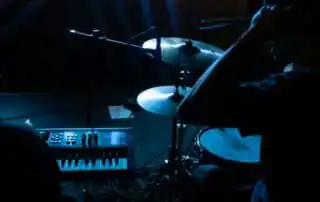Two people behind a drum and piano playing for event