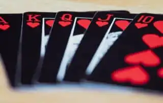 A royal flush in hearts, featuring Ace, King, Queen, Jack, and 10 of hearts, fanned out against a blurred background these are what magicians use for their event