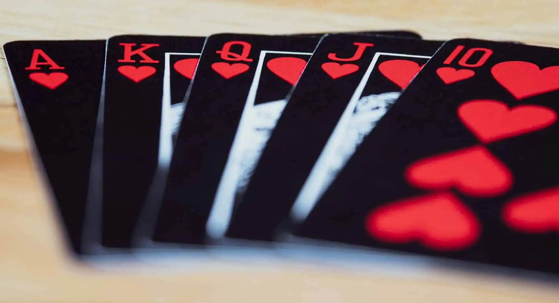 A royal flush in hearts, featuring Ace, King, Queen, Jack, and 10 of hearts, fanned out against a blurred background these are what magicians use for their event