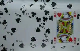 A scattered arrangement of playing cards featuring the Queen of Hearts prominently on top, surrounded by cards like the Four of Clubs, Four of Spades, and Nine of Clubs