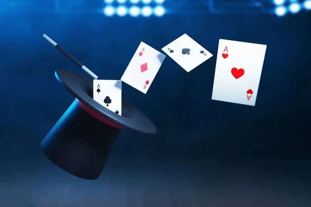 A black top hat of mentalist with a red band, a magic wand, and three floating playing cards
