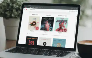 A laptop displaying different types of playlists, each with colorful album art and bold titles