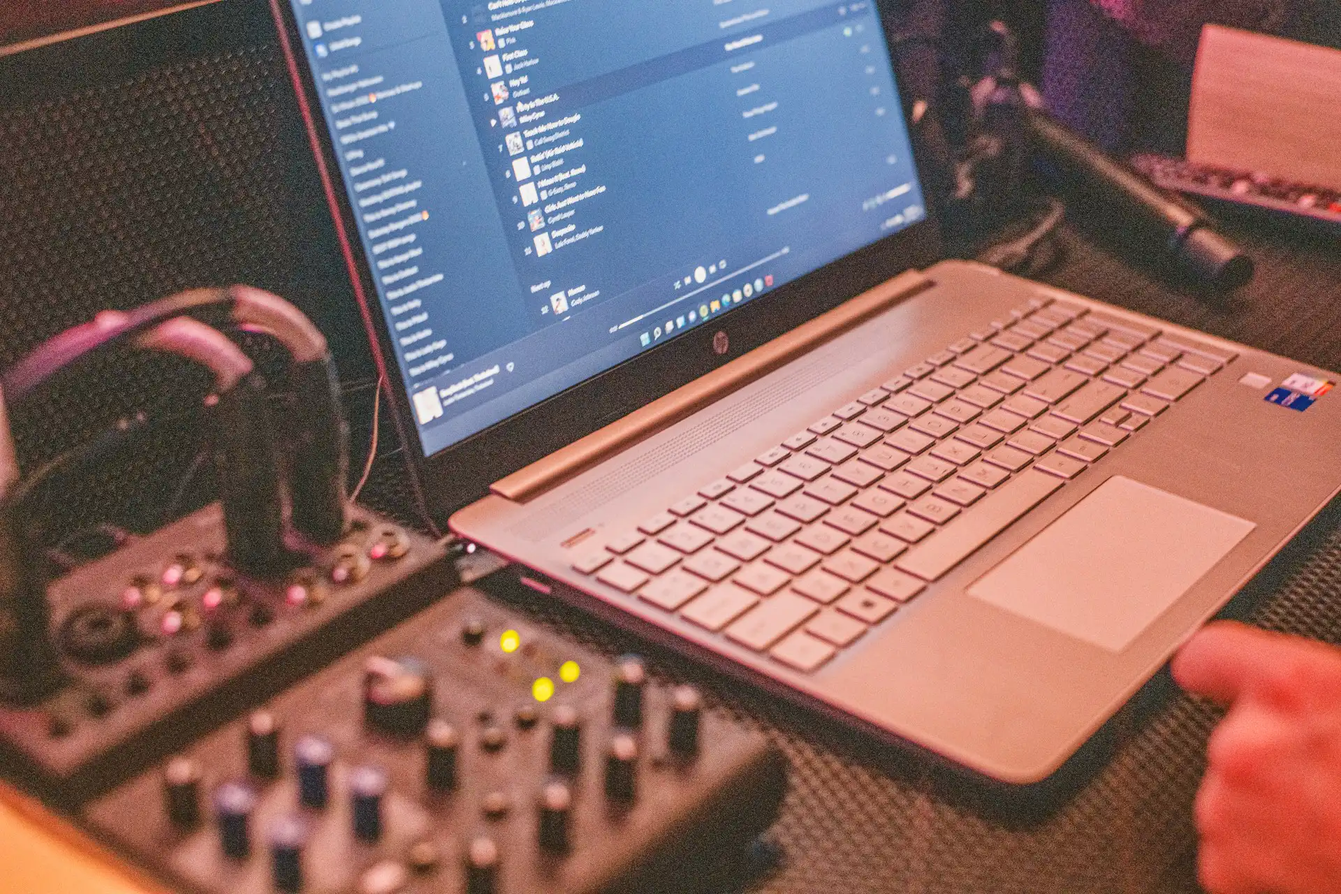 A mixer and a laptop displaying a list of curated music playlists