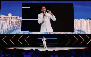 Corporate Event DJ Will Gill is onstage and on screen for Hilton Corporate Conference doing engagement reduces costs and program risks