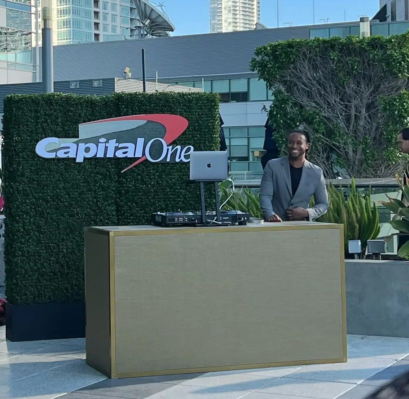 DJ Will Gill at a corporate event booth with a laptop showing a music library, illustrating the balance between do-not-play restrictions and room energy