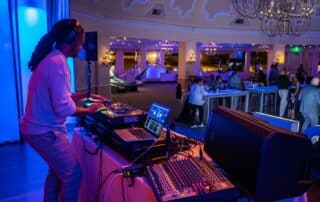 DJ Will Gill mixing a custom playlist in Serato DJ at a corporate event, with turntable, mixer, and laptop