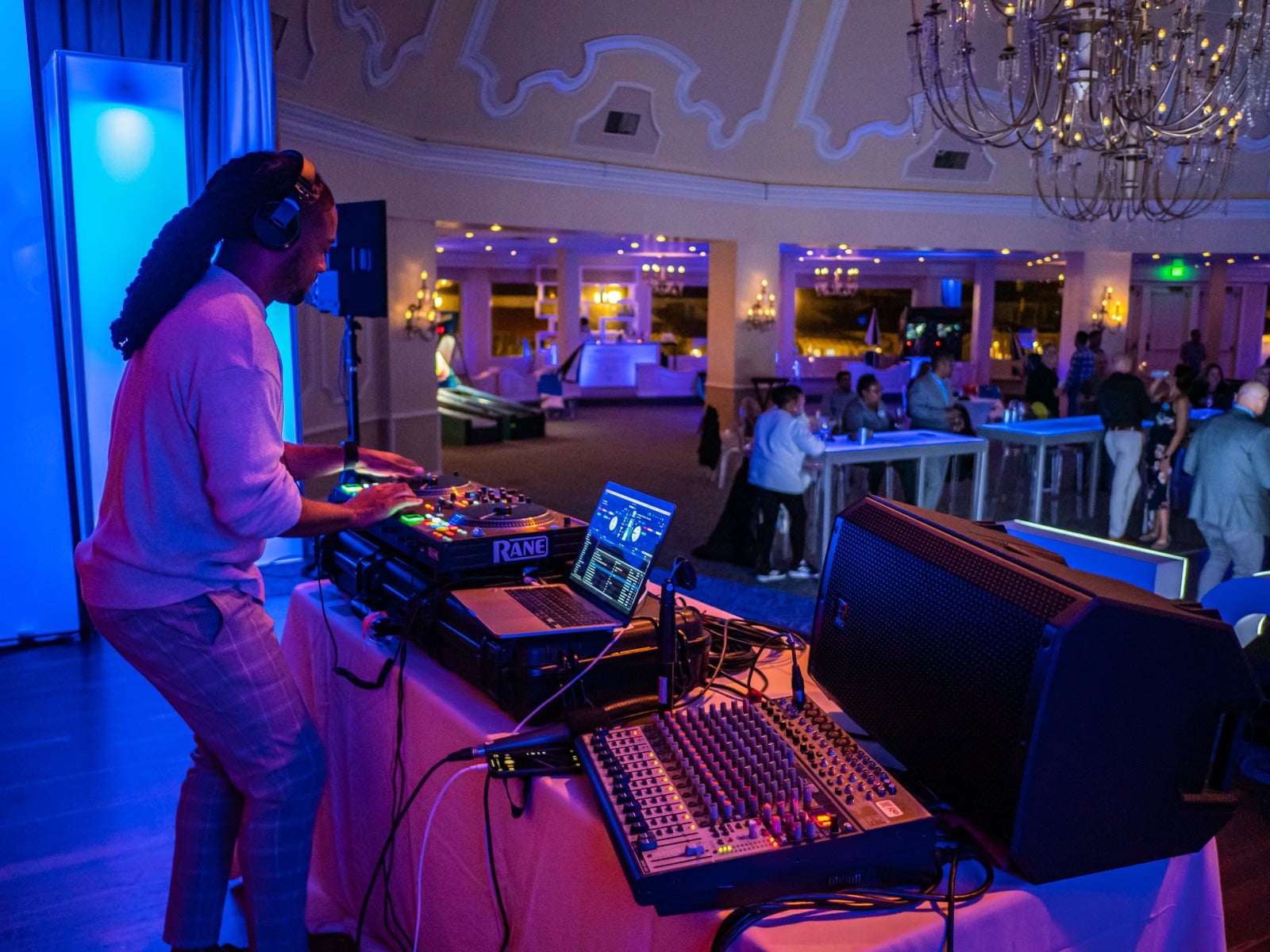 DJ Will Gill mixing a custom playlist in Serato DJ at a corporate event, with turntable, mixer, and laptop