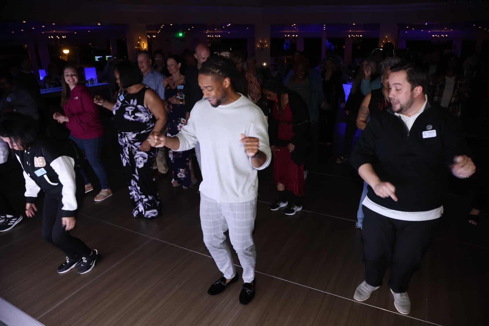 DJ Will Gill dancing with the crowd on the dance floor at a corporate event